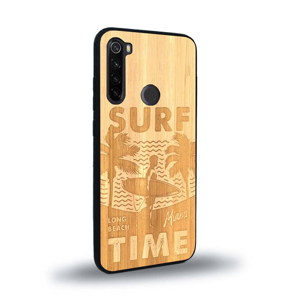 Coque de protection en bois véritable fabriquée en France pour Xiaomi Redmi Note 8 sur le thème chill avec un motif représentant une silouhette tenant une planche de surf sur une plage entouré de palmiers et les mots "Surf Time Long Beach Miami"