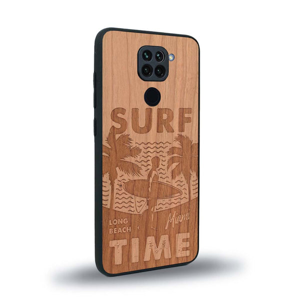 Coque de protection en bois véritable fabriquée en France pour Xiaomi Redmi Note 9 sur le thème chill avec un motif représentant une silouhette tenant une planche de surf sur une plage entouré de palmiers et les mots "Surf Time Long Beach Miami"