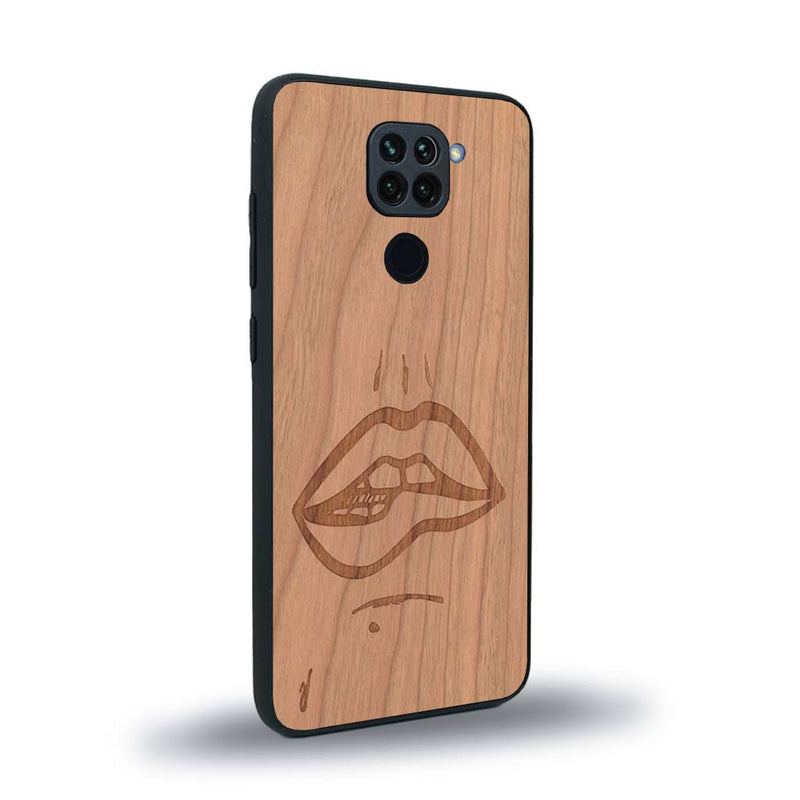 Coque de protection en bois véritable fabriquée en France pour Xiaomi Redmi Note 9 représentant de manière minimaliste une bouche de féminine se mordant le coin de la lèvre de manière sensuelle dessinée à la main par l'artiste Maud Dabs