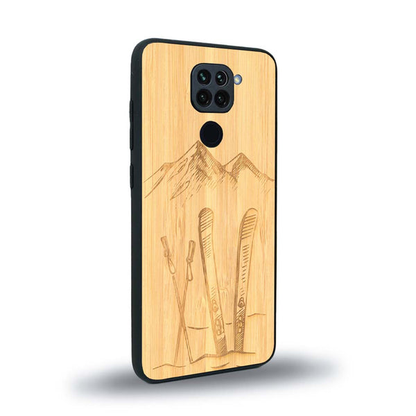 Coque de protection en bois véritable fabriquée en France pour Xiaomi Redmi Note 9 sur le thème de la montagne, du ski et de la neige avec un motif représentant une paire de ski plantée dans la neige avec en fond des montagnes enneigées