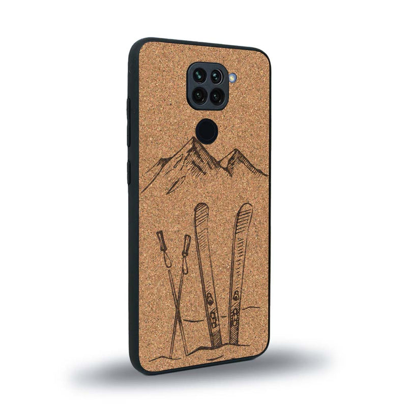 Coque de protection en bois véritable fabriquée en France pour Xiaomi Redmi Note 9 sur le thème de la montagne, du ski et de la neige avec un motif représentant une paire de ski plantée dans la neige avec en fond des montagnes enneigées